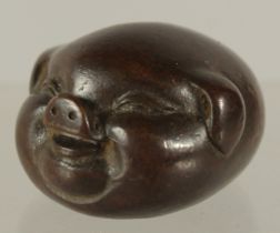 A BRONZE OKIMONO OF A STYLISED PIG, 4cm long.