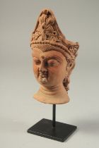A SOUTH EAST ASIAN TERRACOTTA HEAD, raised on a purpose-made stand, head 17.5cm high.