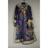 A CHINESE EMBROIDERED BLUE SILK ROBE, adorned with threaded floral sprays and panels of figures.