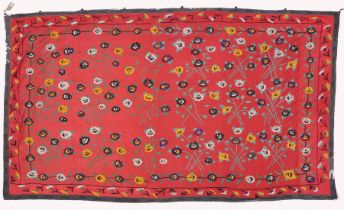 AN UZBEK SUZANI EMBROIDERED TEXTILE, with floral decoration on red ground, 325cm x 224cm.