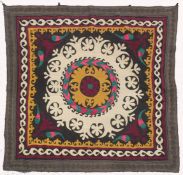 AN UZBEK SUZANI EMBROIDERED TEXTILE, with central foliate motif in mustard yellow, green, maroon,