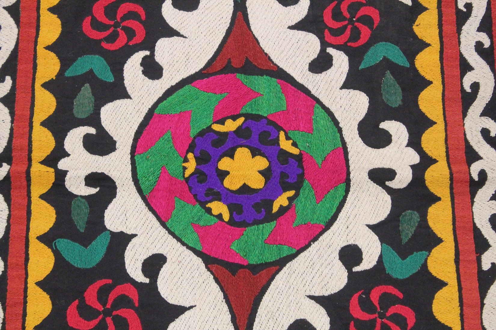 AN UZBEK SUZANI EMBROIDERED TEXTILE, with central foliate motif in purple, yellow, green, red, - Image 2 of 3