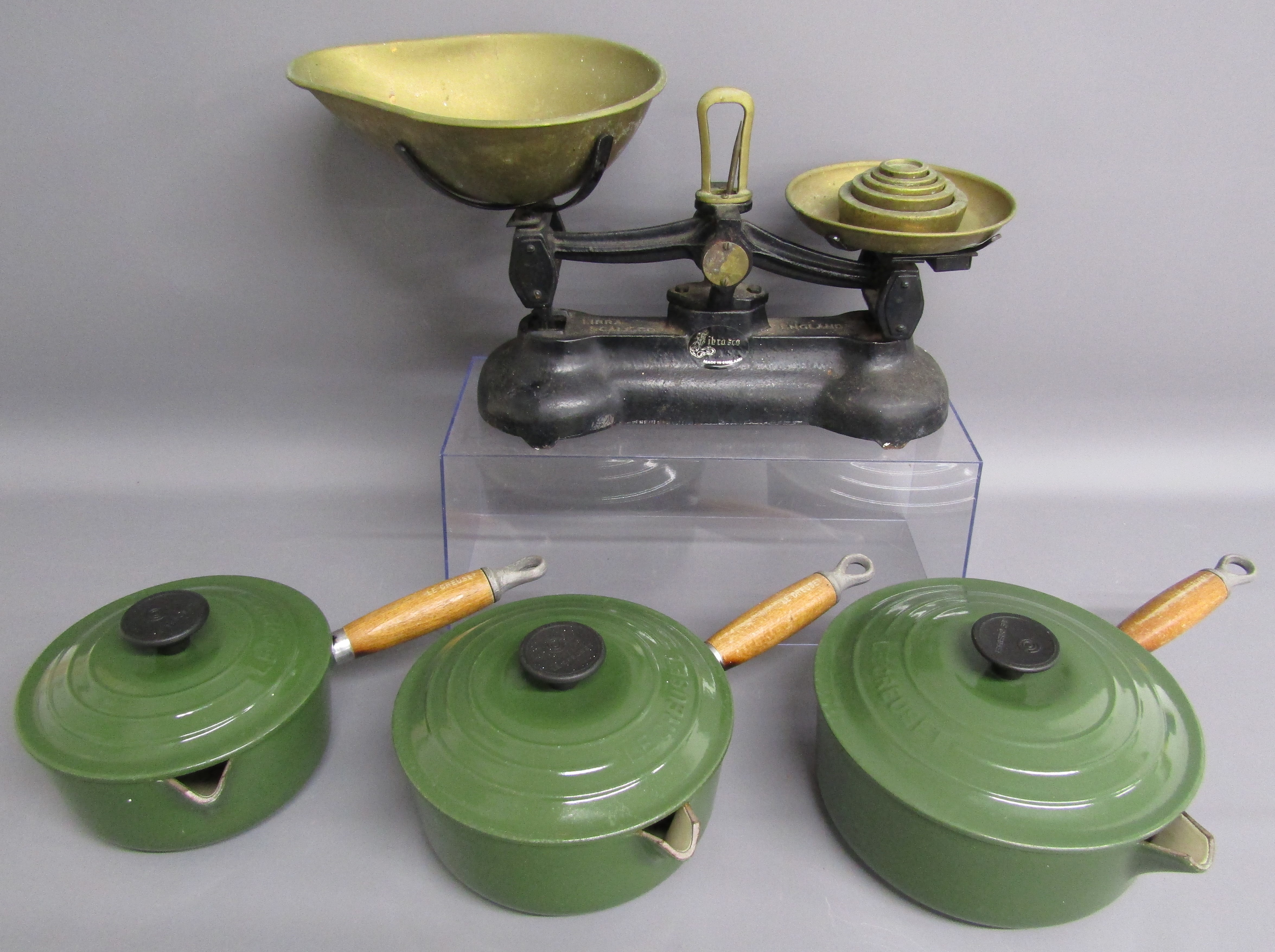 Libra Scale Co scales with weights and 3 green Le Creuset pans with lids and wooden Le Creuset