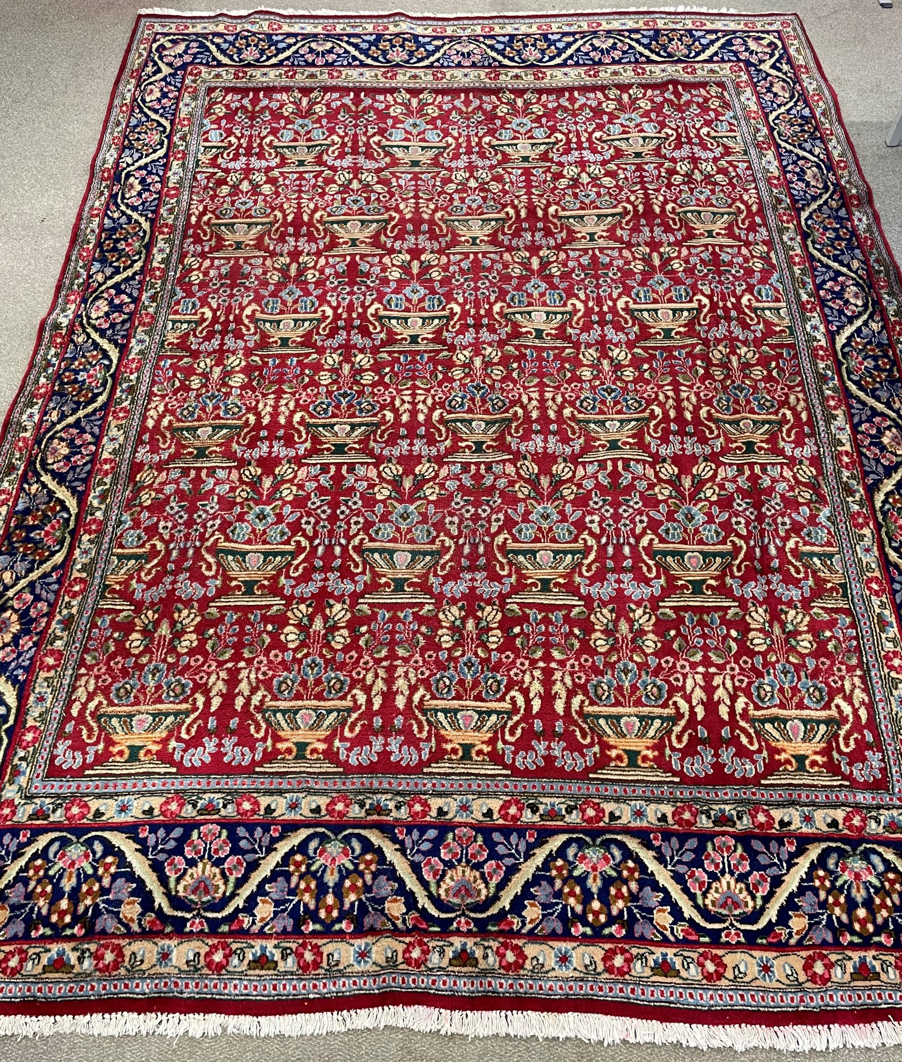 Rich red ground Persian carpet with all over floral design with blue border 330cm by 240cm