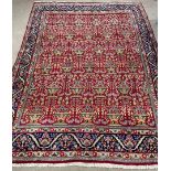 Rich red ground Persian carpet with all over floral design with blue border 330cm by 240cm