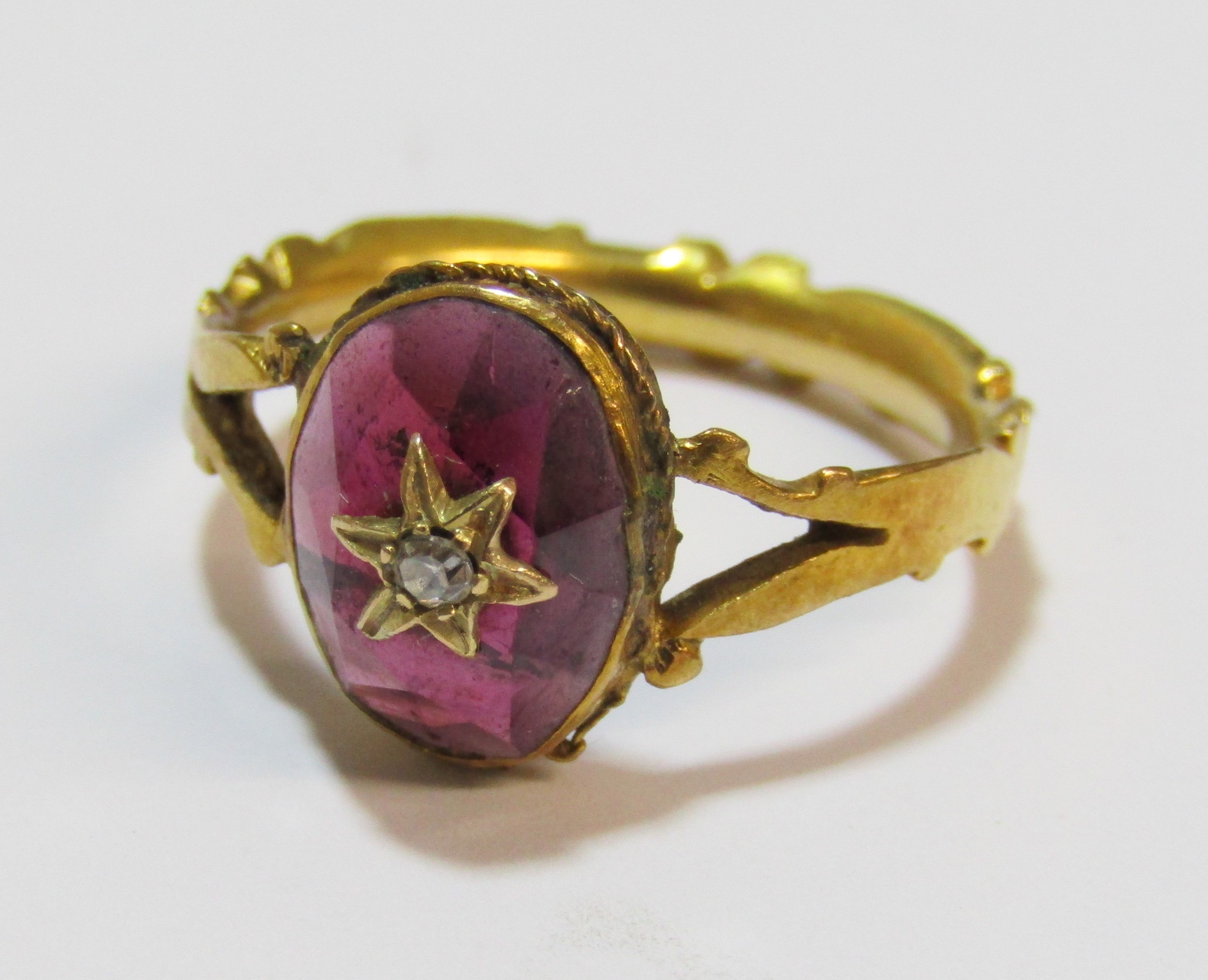Tested as 18ct gold ring with oval garnet cabochon stone decorated with star design and single