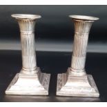 Pair of small silver candlesticks with removable nozzles, fluted bodies and stepped square loaded