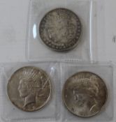 Two one dollar peace coins and an engraved Morgan coin