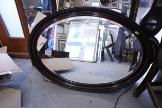 A bevelled plate oval mirror, 29" x 20", in grained as mahogany frame, and an oak hymn board