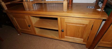 A modern light oak television stand/sideboard, fitted central recess flanked by cupboards, on square