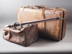 A leather suitcase, another similar, a leather Gladstone bag, a walking cane with white metal top