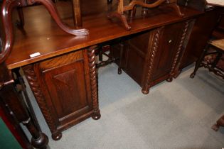 An oak twin pedestal desk, fitted drawers and cupboards with split barley twist pilasters, on bun