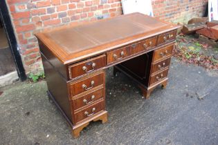 A reproduction twin pedestal desk with tooled leather top over nine drawers, on bracket supports,