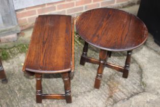 An oak oval drop leaf low occasional table, on turned and stretchered supports, 23" wide x 12"