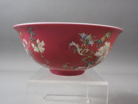A Chinese porcelain bowl with floral and scrolled decoration on a crimson ground, seal mark to base,
