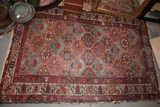 A tribal rug with numerous medallions in shades of red, blue and natural, 82" x 54" approx (worn