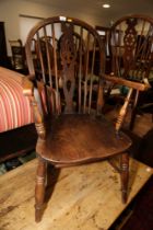 An oak Windsor wheelback armchair with panel seat, on turned and stretchered supports