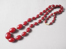 A cherry amber Bakelite bead necklace, the largest oval bead, 27mm long, 68.5g gross
