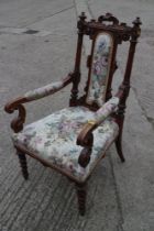 A carved oak armchair with floral upholstered back and seat, on barley twist supports