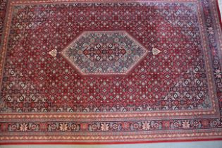A Royal Keshan wool pile carpet of traditional design on a red ground, 122" x 79" approx