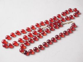 A cherry amber Bakelite bead necklace, the largest round bead, 15mm dia, 60g gross, and another