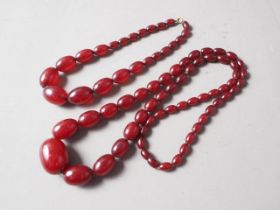 A cherry amber Bakelite bead necklace, the largest oval bead, 34mm long, 71.6g gross, and another