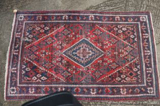 A Caucasian rug with central blue diamond gul on a red ground, 81" x 49" approx (worn)