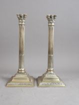 A pair of silver plated Corinthian column candlesticks, on square bases, 12" high