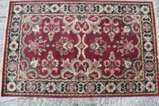 An Indian Agra tea washed wool carpet with floral medallions on a claret ground, 96" x 60" approx