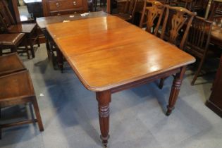 An early 20th century walnut extending dining table with two leaves, on turned castored supports,
