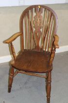 A Windsor wheelback elbow chair with elm panel seat, on turned and stretchered supports