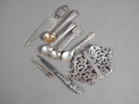 Four silver condiment spoons, a nurse's silver buckle, a white metal book mark, a miniature