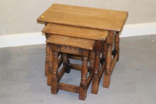 A nest of three oak occasional tables, on turned and stretchered splay supports, 24" wide x 13" deep