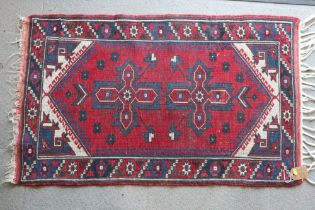 A Caucasian tribal rug with geometric centre on a red ground, 44" x 27" approx