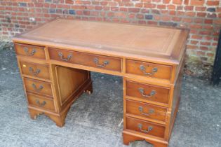 A yew wood double pedestal desk with tooled and gilt leather top over nine drawers, on bracket