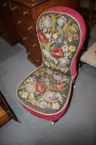 A late 19th century low seat nursing chair with gros point needlework seat and back, on turned and
