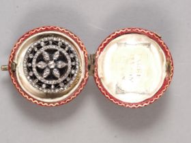 An early 19th century yellow metal circular memento brooch set old cut diamonds over black enamel,