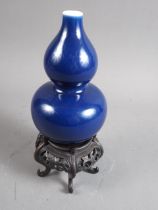A Chinese monochrome blue glazed double gourd vase, 7 1/4" high, on hardwood stand