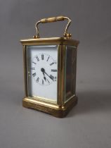 A late 19th century brass cased carriage clock with enamelled dial, inscribed to "Rev J Omelvena