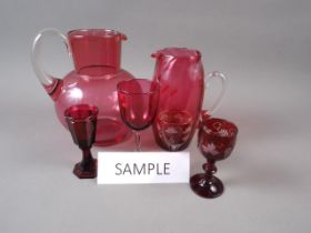 A 19th century faceted ruby glass liqueur, 4" high, four cranberry glass jugs, tallest 7 1/2"