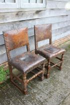 A pair of 18th century oak chairs with seats and back upholstered in a brown leather, on turned