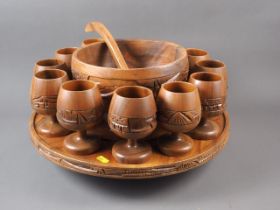 A turned wood punch bowl and ladle, twelve matching goblets and a matching lazy Susan
