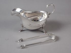 A silver sauce boat and a pair of Georgian silver sugar tongs with bright cut decoration, 5.7oz troy