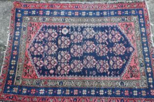 A Caucasian rug with floral design, on a dark blue ground and triple bordered in shades of red,