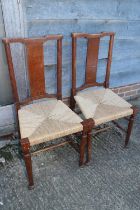 A pair of William Morris "Hampton Court" oak and hardwood panel back side chairs with string
