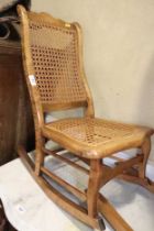 A child's polished as walnut rocking chair with cane seat and back panels