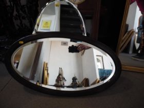 A mahogany oval wall mirror with bevelled plate, 23" x 11 1/2"