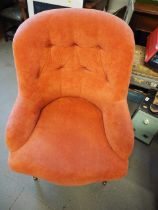 A tub chair, button upholstered in a salmon velour, on turned and castored supports