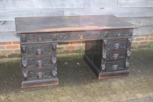 A late 19th century carved oak double pedestal desk, fitted nine drawers with lion mask handles,