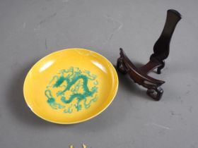 A Chinese porcelain shallow dish, decorated dragons on a yellow ground, four-character mark to base,